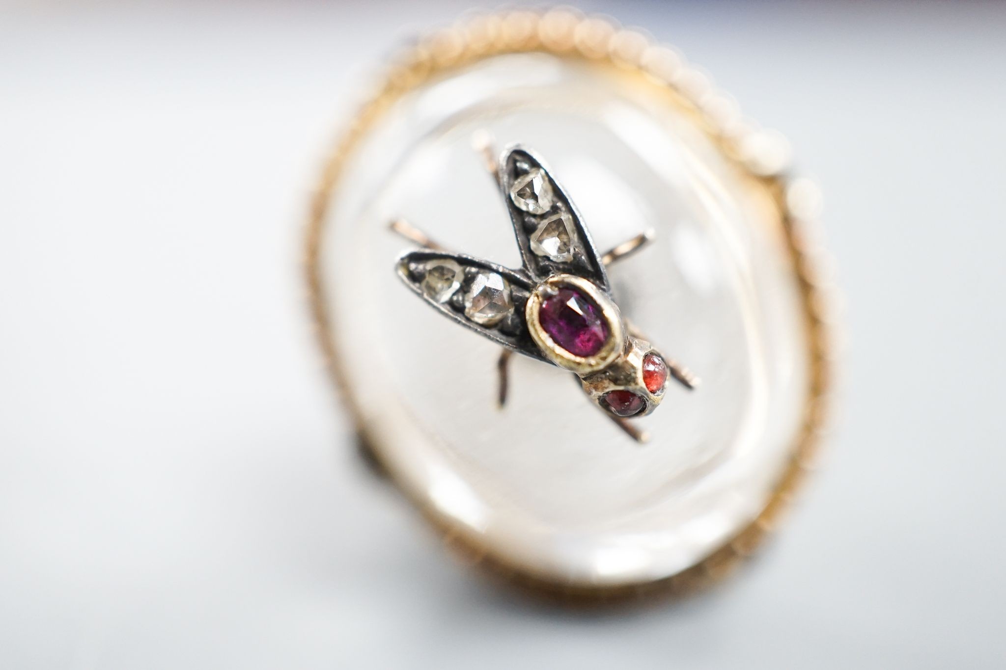 A Victorian, yellow metal and cabochon rock crystal? set dress ring, with central gem set bug motif, size R/S, gross weight 12.4 grams.